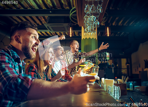 Image of Sport, people, leisure, friendship and entertainment concept - happy football fans or male friends drinking beer and celebrating victory at bar or pub