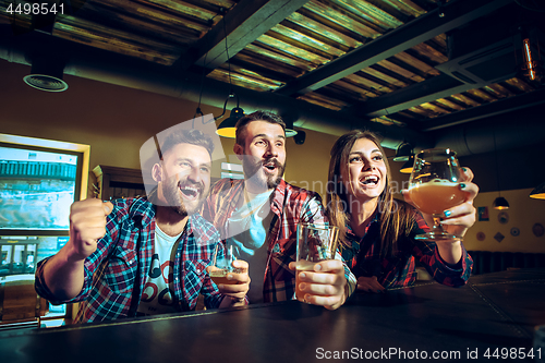 Image of Sport, people, leisure, friendship and entertainment concept - happy football fans or male friends drinking beer and celebrating victory at bar or pub