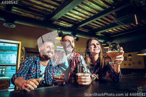 Image of Sport, people, leisure, friendship and entertainment concept - happy football fans or male friends drinking beer and celebrating victory at bar or pub