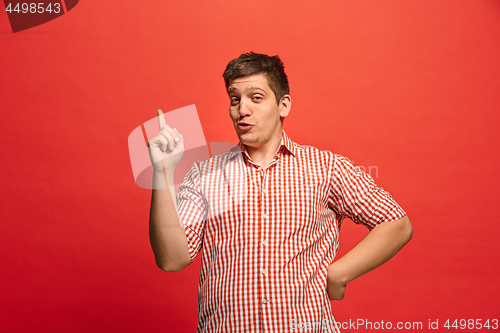 Image of Beautiful male half-length portrait isolated on red studio backgroud. The young emotional surprised man