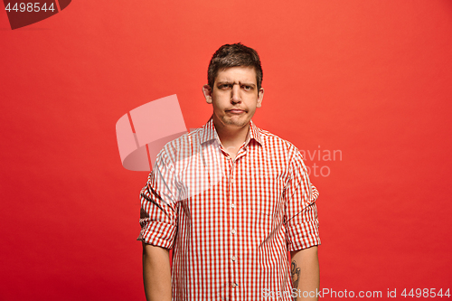 Image of Beautiful male half-length portrait isolated on red studio backgroud. The young emotional surprised man