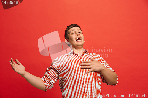 Image of The happy business man standing and smiling against red background.