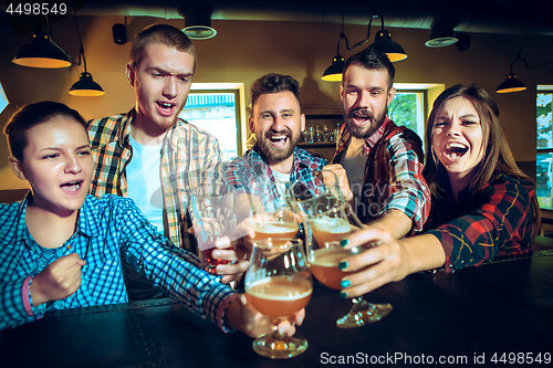 Image of Sport, people, leisure, friendship and entertainment concept - happy football fans or male friends drinking beer and celebrating victory at bar or pub