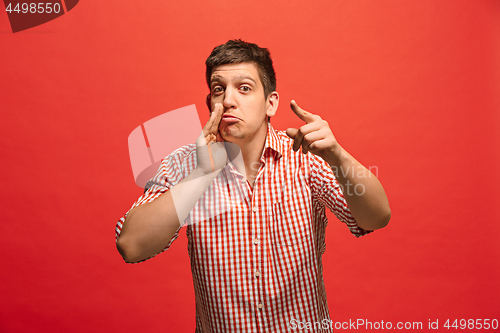 Image of The young man whispering a secret behind her hand over red background