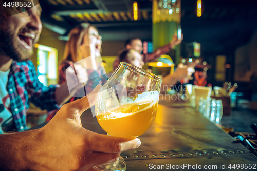 Image of Sport, people, leisure, friendship and entertainment concept - happy football fans or male friends drinking beer and celebrating victory at bar or pub