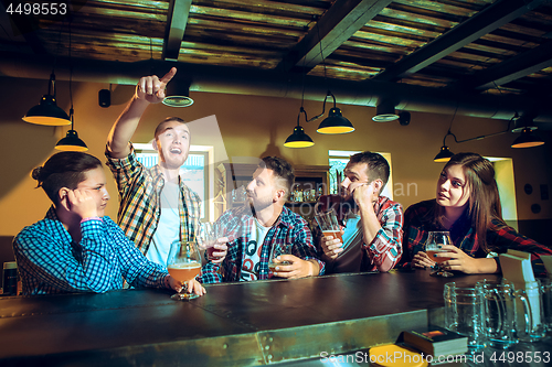 Image of Sport, people, leisure, friendship and entertainment concept - happy football fans or male friends drinking beer and celebrating victory at bar or pub