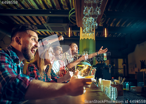 Image of Sport, people, leisure, friendship and entertainment concept - happy football fans or male friends drinking beer and celebrating victory at bar or pub