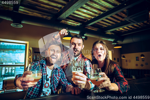 Image of Sport, people, leisure, friendship and entertainment concept - happy football fans or male friends drinking beer and celebrating victory at bar or pub