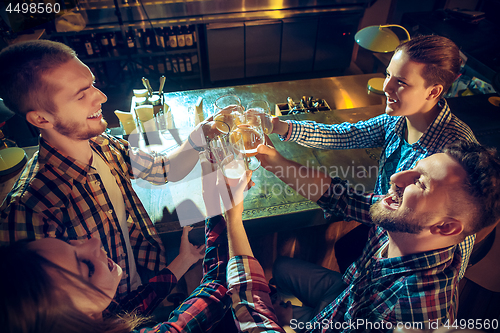 Image of Sport, people, leisure, friendship and entertainment concept - happy football fans or male friends drinking beer and celebrating victory at bar or pub