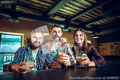 Image of Sport, people, leisure, friendship and entertainment concept - happy football fans or male friends drinking beer and celebrating victory at bar or pub