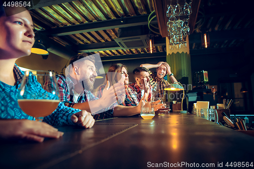 Image of Sport, people, leisure, friendship and entertainment concept - happy football fans or male friends drinking beer and celebrating victory at bar or pub