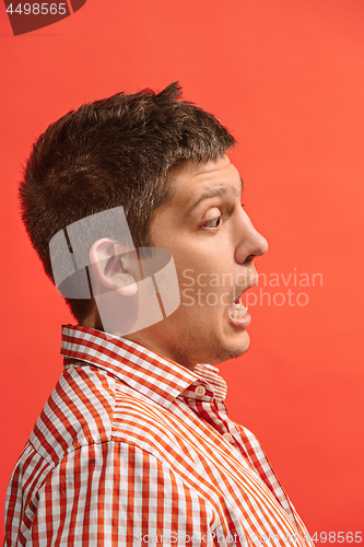 Image of The young attractive man looking suprised isolated on red