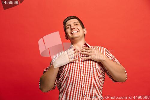 Image of The happy business man standing and smiling against red background.