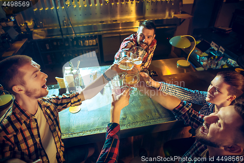 Image of Sport, people, leisure, friendship and entertainment concept - happy football fans or male friends drinking beer and celebrating victory at bar or pub