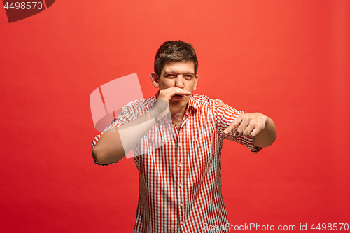 Image of The young man whispering a secret behind her hand over red background