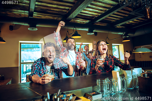 Image of Sport, people, leisure, friendship and entertainment concept - happy football fans or male friends drinking beer and celebrating victory at bar or pub