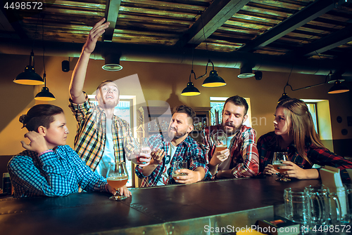 Image of Sport, people, leisure, friendship and entertainment concept - happy football fans or male friends drinking beer and celebrating victory at bar or pub