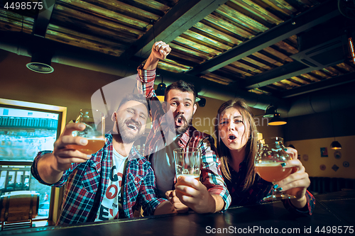 Image of Sport, people, leisure, friendship and entertainment concept - happy football fans or male friends drinking beer and celebrating victory at bar or pub