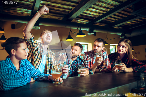 Image of Sport, people, leisure, friendship and entertainment concept - happy football fans or male friends drinking beer and celebrating victory at bar or pub