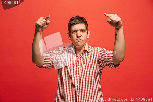 Image of The young emotional angry man screaming on red studio background