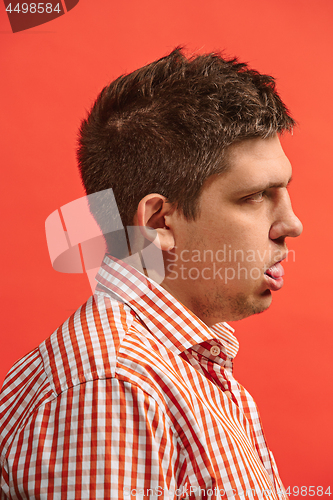 Image of Doubtful pensive man with thoughtful expression making choice against red background