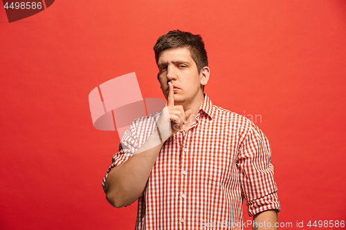 Image of The young man whispering a secret behind her hand over green background