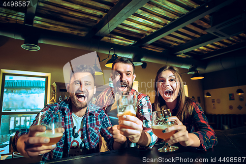 Image of Sport, people, leisure, friendship and entertainment concept - happy football fans or male friends drinking beer and celebrating victory at bar or pub