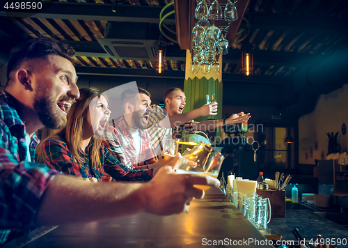 Image of Sport, people, leisure, friendship and entertainment concept - happy football fans or male friends drinking beer and celebrating victory at bar or pub