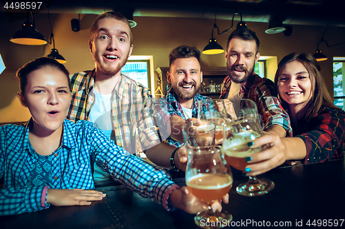 Image of Sport, people, leisure, friendship and entertainment concept - happy football fans or male friends drinking beer and celebrating victory at bar or pub