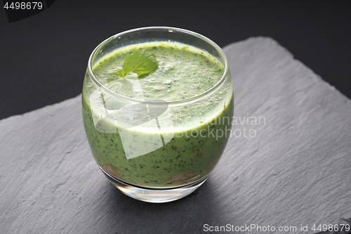 Image of Green smoothie made from spinach, kale, avocado and banana garnished with a mint leaf.