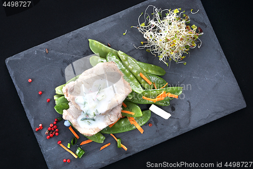 Image of Lunch. Low-cost, balanced diet. Cooked meat on a sweet pea salad served with white yoghurt sauce.