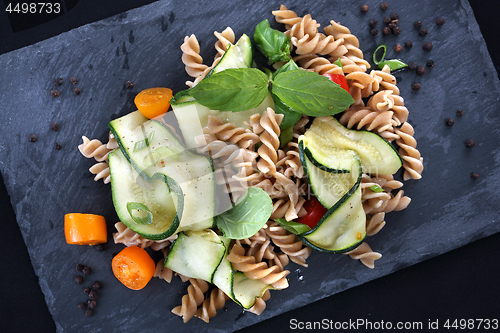 Image of Macaroni salad. Spiral pasta with vegetables. on a black plate.