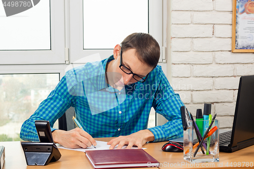 Image of An office worker writes a statement at the table