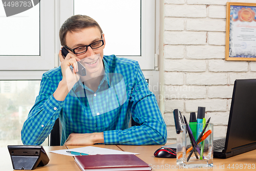 Image of Office specialist with a smile talking on the phone