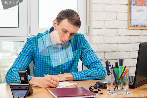 Image of Young office specialist at the table writes a statement