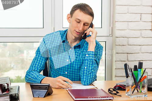 Image of Specialist in the office talking on the phone in preparation for recording information