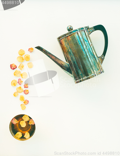 Image of Vintage teapot and cup of tea with rose petals