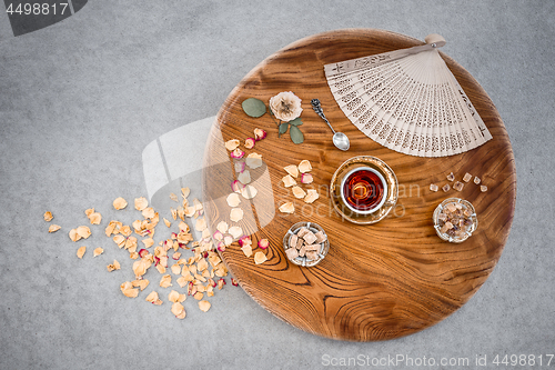 Image of Vintage wooden table with tea and rose petals