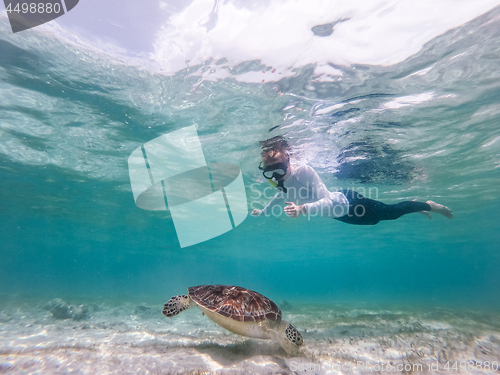 Image of Woman on vacations wearing snokeling mask swimming with sea turtle in turquoise blue water of Gili islands, Indonesia. Underwater photo.