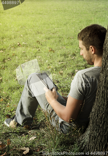 Image of Young man reading e-book