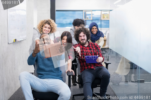 Image of multiethnics business team racing on office chairs