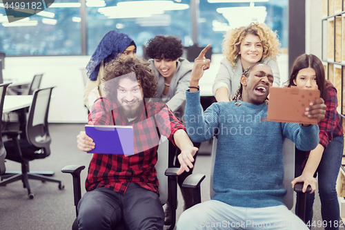 Image of multiethnics business team racing on office chairs