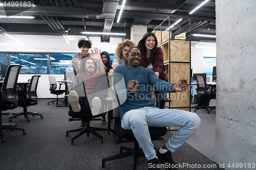 Image of multiethnics business team racing on office chairs