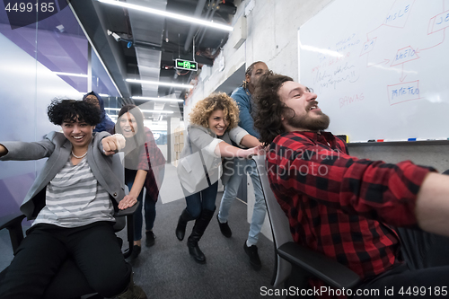 Image of multiethnics business team racing on office chairs