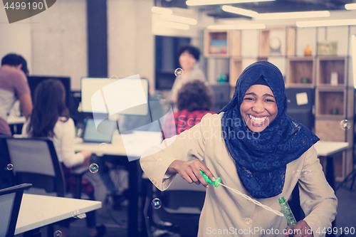 Image of black muslim software developer making soap bubble