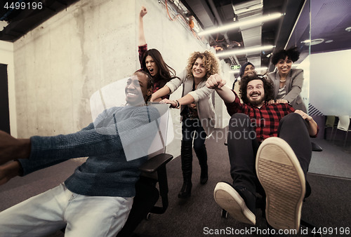 Image of multiethnics business team racing on office chairs