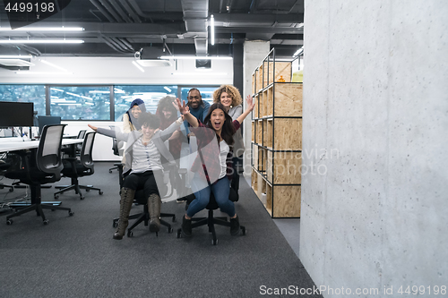 Image of multiethnics business team racing on office chairs