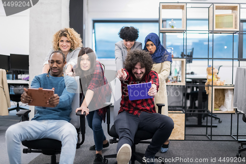 Image of multiethnics business team racing on office chairs