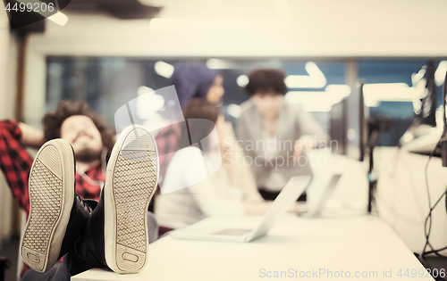 Image of software developer resting with legs on desk