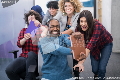 Image of multiethnics business team racing on office chairs